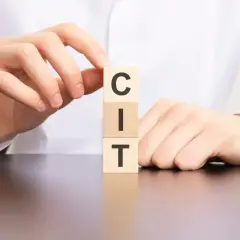 Dłonie układają kostki z literami C, I, T, tworząc słowo "CIT".