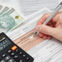 Działalność nierejestrowana a kwota wolna od podatku. Kalkulator i pieniądze na zeznaniu podatkowym.