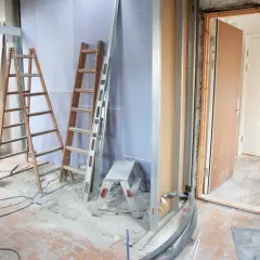 Remont mieszkania w toku. Drabiny, materiały budowlane i otwarte drzwi sugerują, że trwa praca. Zastanawiasz się, za ile sprzedać mieszkanie do remontu?