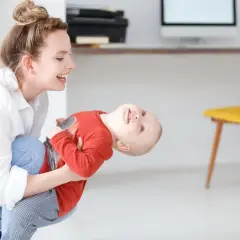Szczęśliwa mama bawi się z dzieckiem, planując dopłatę do żłobka.