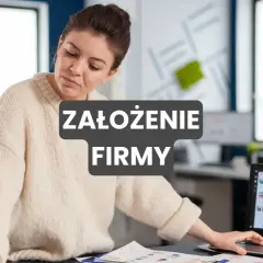 Kobieta pracuje nad dokumentami, przygotowując się do założenia firmy. Na ekranie laptopa widoczne są wykresy.