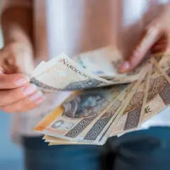 Ręce trzymające polskie banknoty 200 zł. Zastanawiasz się, jak zgłosić spadek w gotówce?