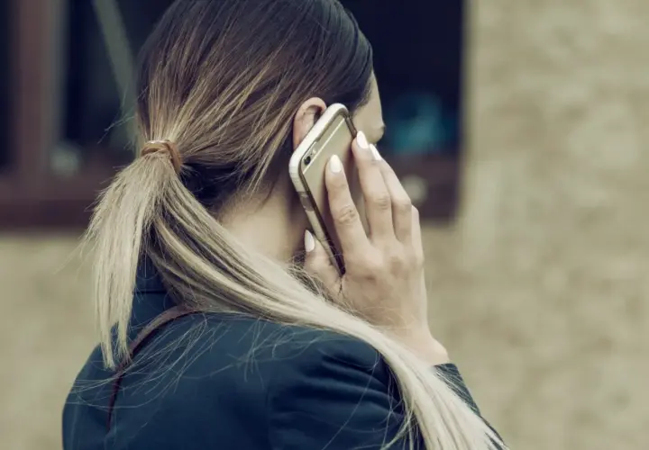 Kobieta z blond kucykiem rozmawia przez telefon, zastanawiając się, czy można odmówić urlopu na żądanie.