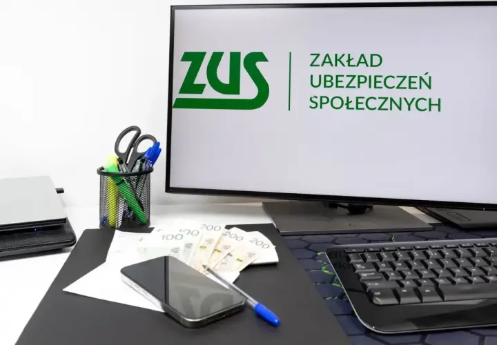 Biurko z monitorem ZUS, telefonem, pieniędzmi i artykułami piśmienniczymi. Idealne miejsce dla osoby współpracującej z urzędem.