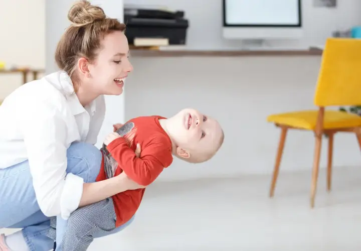 Szczęśliwa mama bawi się z dzieckiem, planując dopłatę do żłobka.