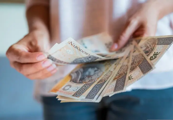 Ręce trzymające polskie banknoty 200 zł. Zastanawiasz się, jak zgłosić spadek w gotówce?