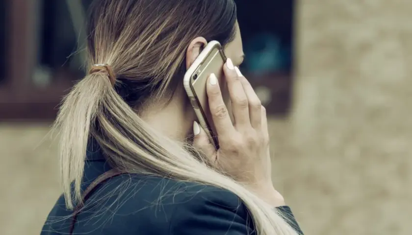 Kobieta z blond kucykiem rozmawia przez telefon, zastanawiając się, czy można odmówić urlopu na żądanie.