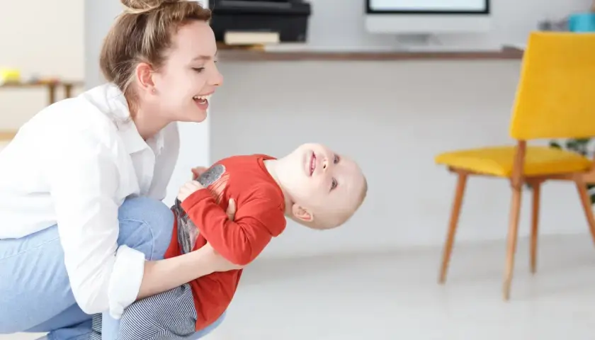 Szczęśliwa mama bawi się z dzieckiem, planując dopłatę do żłobka.