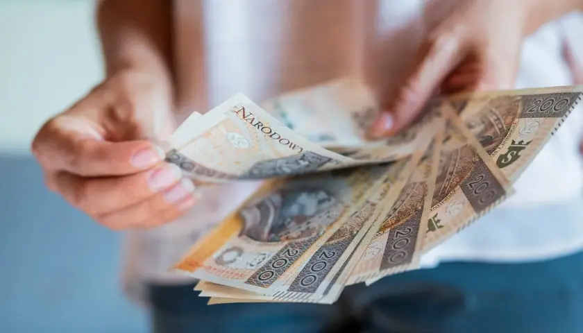 Ręce trzymające polskie banknoty 200 zł. Zastanawiasz się, jak zgłosić spadek w gotówce?