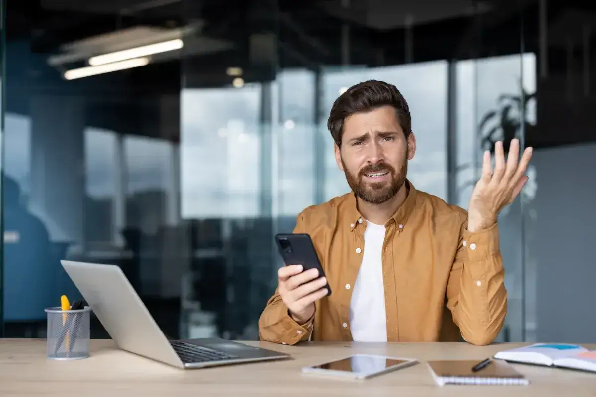 Zmartwiony mężczyzna trzyma telefon, zastanawiając się nad świadczeniem urlopowym 2026.