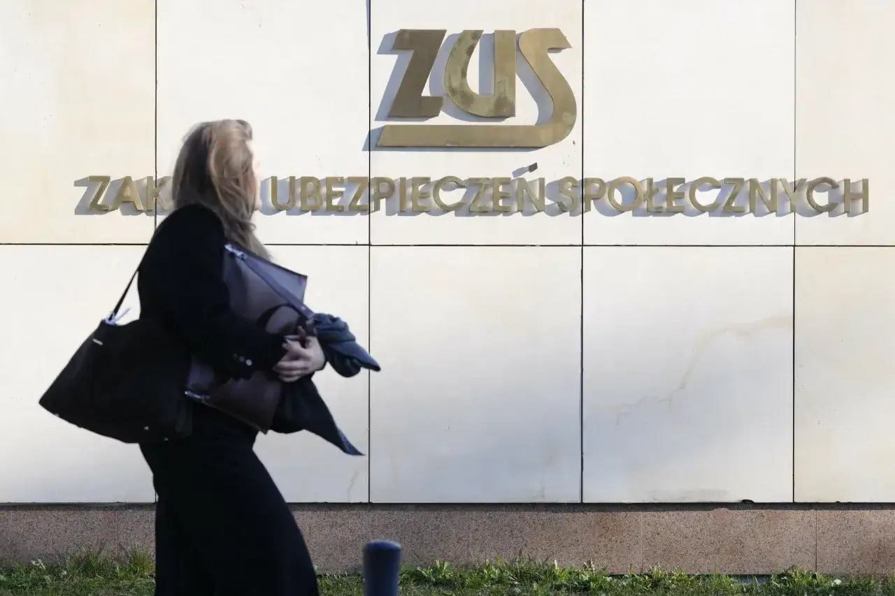 Kobieta z torbami mija budynek ZUS. Temat: wynagrodzenie członka zarządu a ZUS.