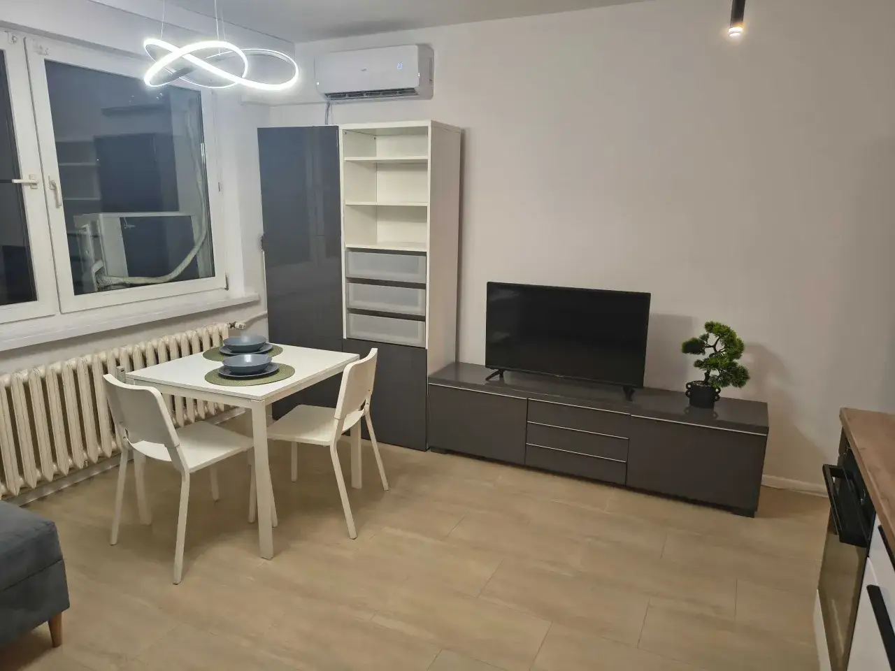 Nowoczesny salon z jadalnią, idealny na najem krótkoterminowy bez działalności. Klimatyzacja, TV, wygodne meble.