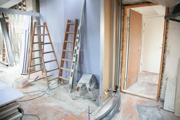 Remont mieszkania w toku. Drabiny, materiały budowlane i otwarte drzwi sugerują, że trwa praca. Zastanawiasz się, za ile sprzedać mieszkanie do remontu?